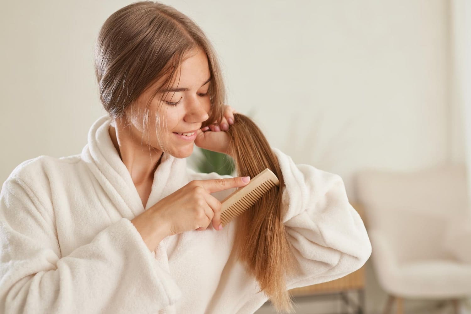 Woman brushing long hair while wearing a bathrobe