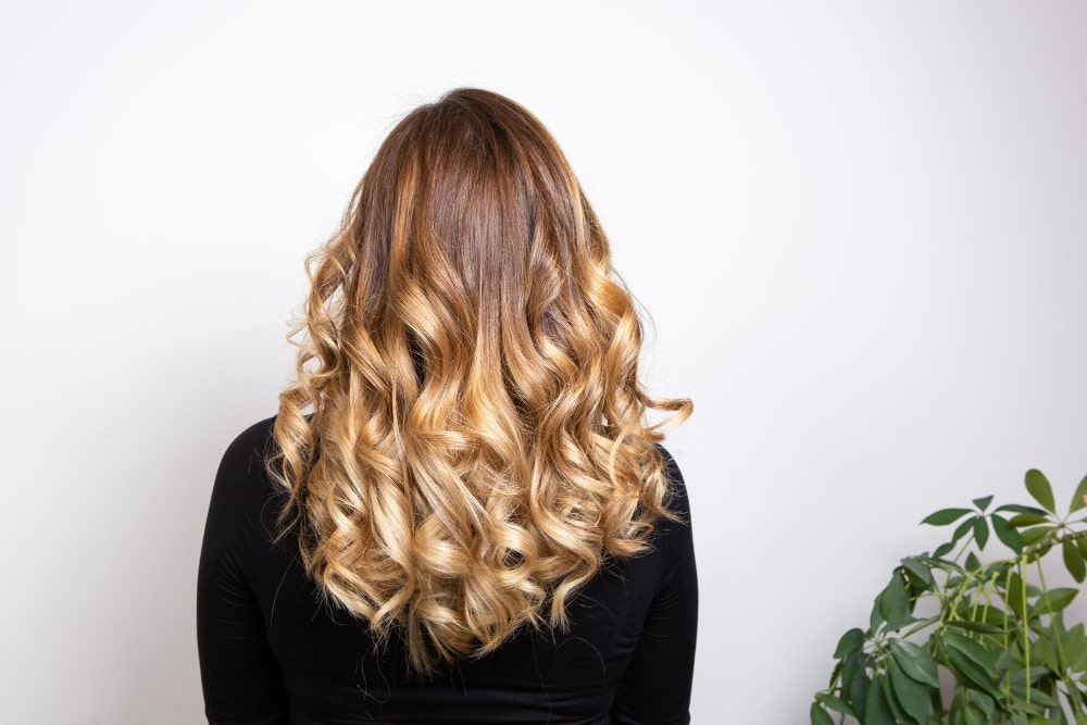 Woman with curly blonde hair featuring an ombre effect, styled in loose waves