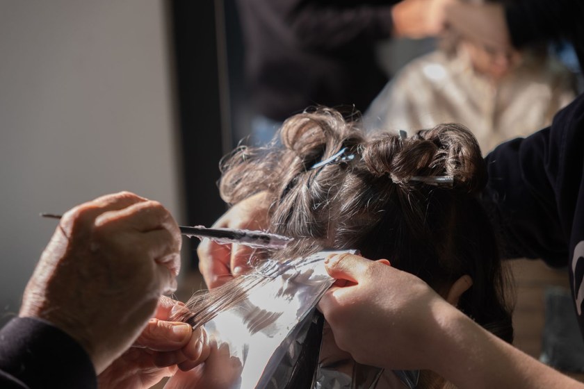 Colorist weaving out a very fine section of hair with a comb above a foil for babylights
