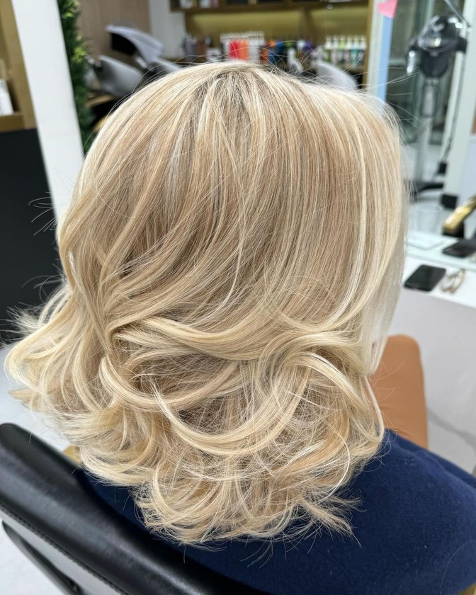 Blonde mid-length hair with round-brush volume after a blowout at HairSocial