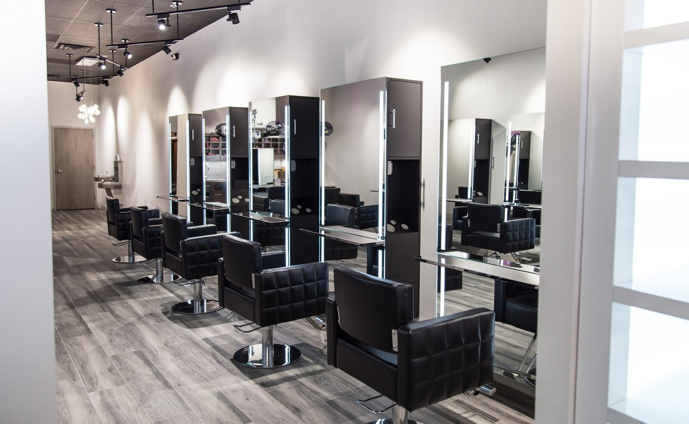 Row of black styling chairs facing lit mirrors on the styling floor at HairSocial in Falls Church