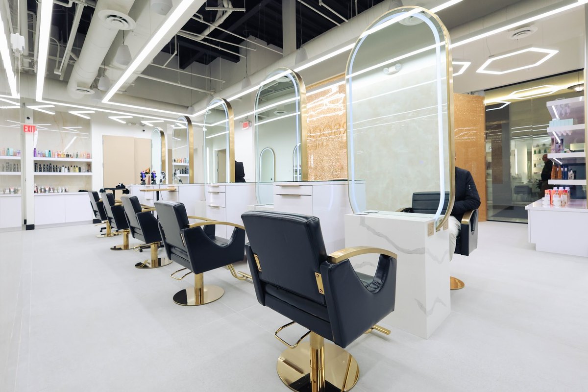Styling stations with lit mirrors and gold-framed chairs on the styling floor at HairSocial in Tysons