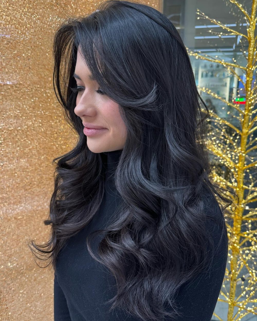 Long layers cut into black hair during a women’s haircut, finished in soft waves