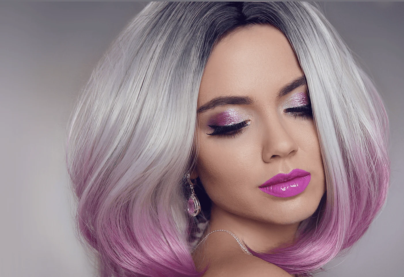 Close-up of a woman with a silver-to-pink ombre bob, hair styled at HairSocial.