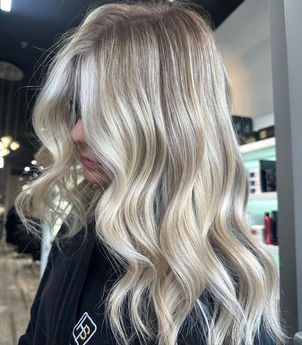 Client with long blonde balayage styled in soft waves at HairSocial