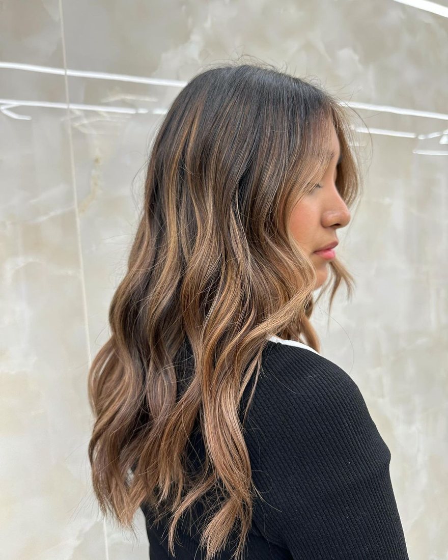 Side view of brunette hair with caramel balayage waves at HairSocial