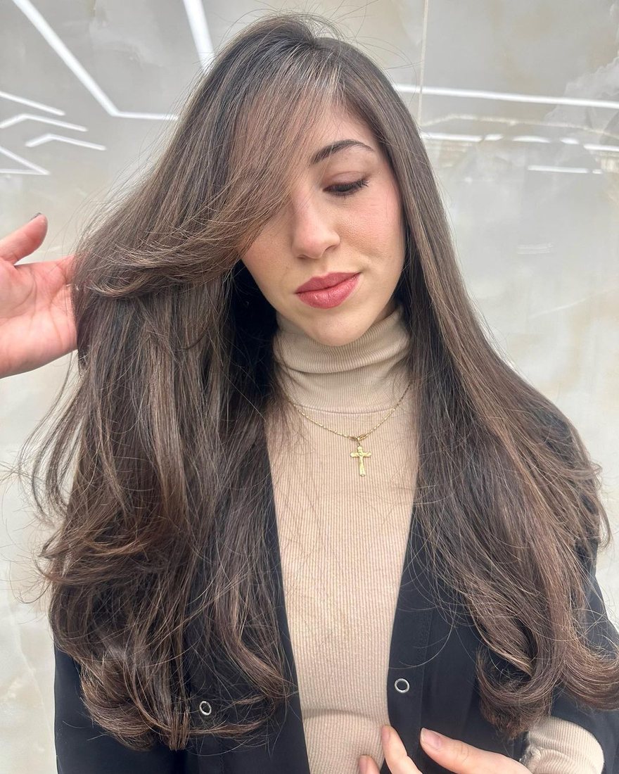 Client with a glossy brunette blowout and face-framing layers at HairSocial
